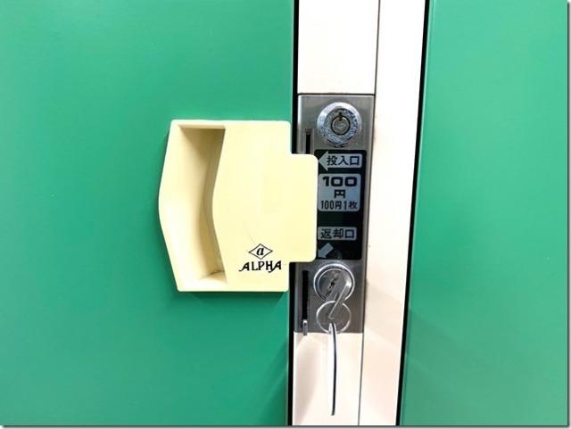 緑の扉の100円投入口と白い取っ手のアップ写真